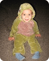 Child in a green animal costume sitting.