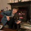 Smiling teen hugging dog by cozy fireplace