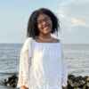 Smiling person in white dress by the sea