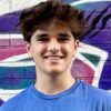 Smiling young man in front of graffiti wall.
